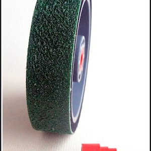 May include: A green sanding wheel with a black rubber backing and a red center. The wheel is about 3 inches in diameter. A red plastic adapter is also shown.