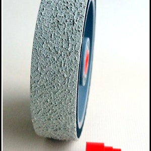 May include: A gray sanding wheel with a textured surface and a red plastic cap.