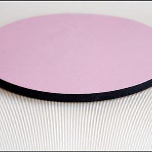 May include: A round, pink, foam coaster with a black edge.