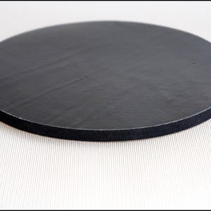 May include: A black round cake board with a black foam edge.