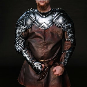 Op de afbeelding: Een middeleeuwse harnasset met een zilverkleurige borstplaat en armbeschermers, gecombineerd met een bruine leren tuniek. Het harnas heeft geklonken details en een riem. De algehele esthetiek suggereert een fantasie- of historisch thema.