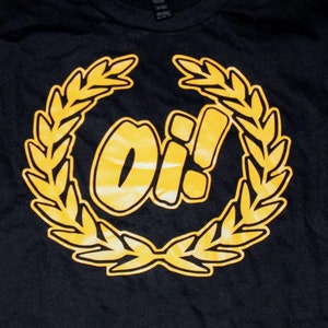 May include: Black t-shirt with a gold laurel wreath design and the word "Oi!" in the center.