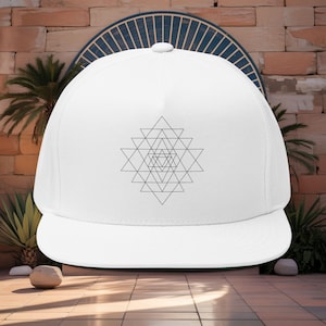 May include: A white flat-peak cap with a geometric black design. The cap has a green underside on the peak. This hat is a fashionable accessory.