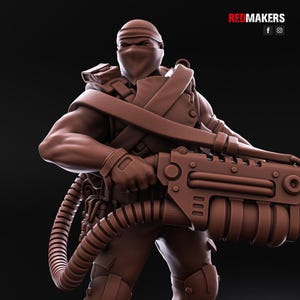 May include: A brown plastic miniature figure of a soldier wearing a black mask and holding a large, detailed, futuristic weapon.