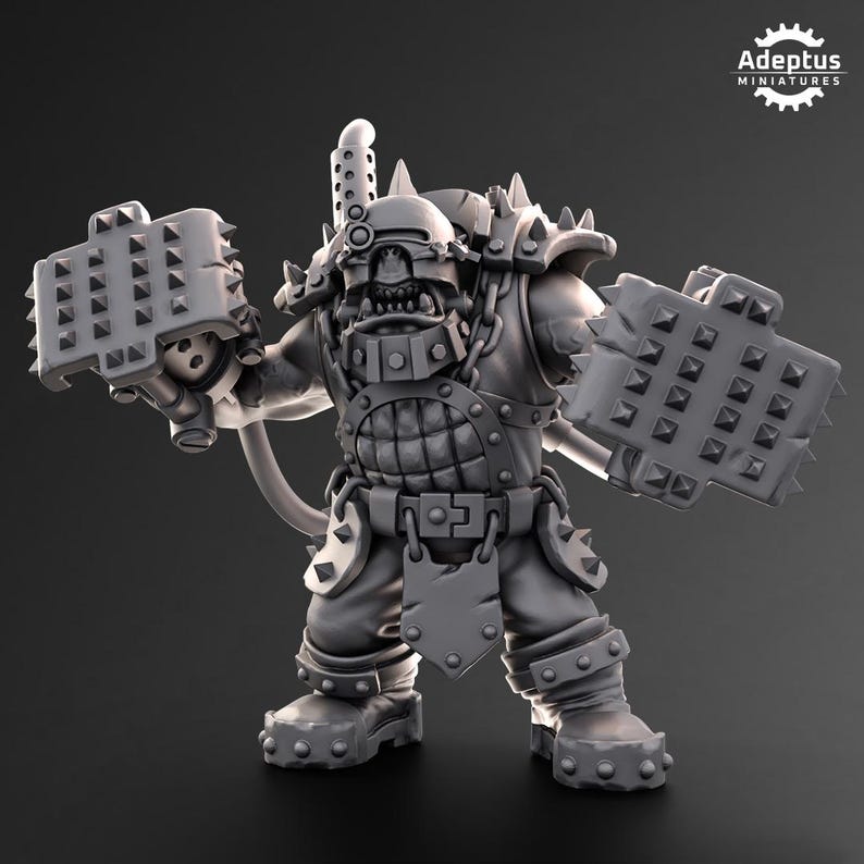 Puede incluir: Figura en miniatura gris de un guerrero orco fuertemente blindado, sosteniendo dos armas con p&uacute;as. La figura tiene un casco, p&uacute;as en los hombros y una placa pectoral con tachuelas. El logotipo de Adeptus Miniatures est&aacute; en la esquina superior derecha.