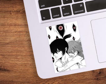 May include: A black and white sticker featuring an anime-style illustration of two figures embracing. The artwork includes multiple floating eyes and detailed character designs. The sticker is rectangular and placed on a laptop.