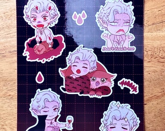 May include: A set of eight stickers featuring a cartoon vampire character in various poses. The stickers are printed on a black background with a grid pattern. The stickers include the text "Astarion" and "Don't touch me".