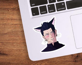 May include: A sticker featuring an anime-style character with black hair, cat ears, and a stern expression. The character has pink blush and is wearing a black outfit. The sticker is placed on a white laptop.
