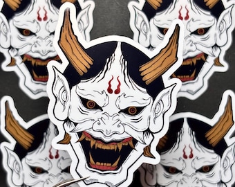 May include: Five white and black Japanese demon mask stickers with red and gold accents. The stickers have a fierce expression with sharp teeth and horns.