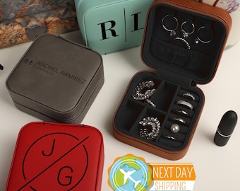 May include: An assortment of personalized jewelry cases in various colors, including red, gray, and teal. One case is open, displaying rings and earrings. The cases feature initials and the text "RACHEL RAMIREZ DESIGNER".