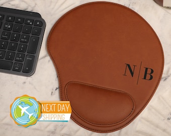 May include: Brown leather mouse pad with a wrist rest and the initials "NB" in black lettering.
