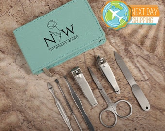May include: A teal leather zippered case with the initials "NW" and the name "Nicholas Ward" printed on it. The case contains a set of six silver manicure tools, including nail clippers, tweezers, a nail file, and a cuticle pusher.