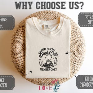 May include: Cream-colored t-shirt with the text "ANTI SOCIAL Book Club MEMBER ONLY" in black. The shirt is displayed on a woven, circular surface. The image also includes text that says "PREMIUM THREADS & FABRICS", "HANDMADE WITH PRECISION", and "HIGH-QUALITY EMBROIDERY FINISHING".
