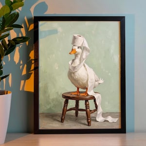 May include: A framed painting of a white duck with an orange beak standing on a small wooden stool. The duck has a roll of white toilet paper balanced on its head, with the paper draped around its neck and trailing down to the floor.