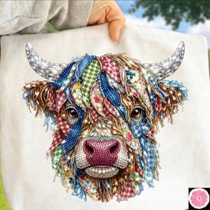 May include: A white tote bag featuring a colorful, detailed illustration of a Highland cow. The cow's fur is a patchwork of patterned fabrics in red, blue, green, and floral designs, with crystal accents. The cow has brown eyes and a pink nose.