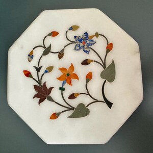 May include: White octagonal marble coaster with a floral design inlaid with colourful stones. The design features orange, blue, green, and red stones.