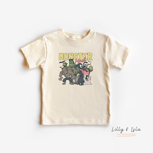 May include: A cream coloured t-shirt with a graphic of monsters and the text "Monster Mash" in yellow.