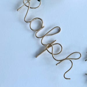 May include: Gold wire name art spelling out the name "Kaleigh".