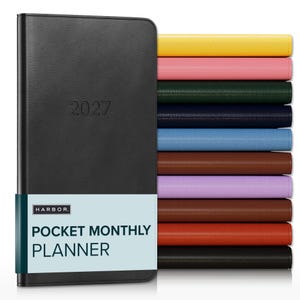 May include: A black 2027 pocket monthly planner with a Harbor brand paper band, displayed alongside a vertical stack of identical planners in yellow, pink, dark green, navy, light blue, brown, lavender, reddish-brown, orange, and black.
