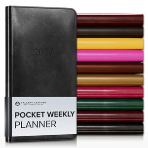May include: A black 2027 pocket weekly planner with a white paper band featuring the text Gallery Leather Bar Harbor, Maine Pocket Weekly Planner. To the right, a stack of ten additional planners in various colors including red, brown, yellow, and pink.