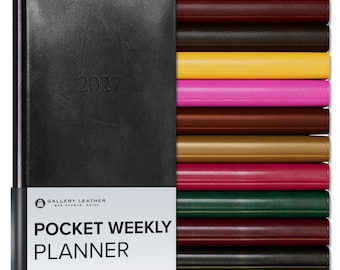 May include: A black 2027 pocket weekly planner with a white paper band featuring the text Gallery Leather Bar Harbor, Maine Pocket Weekly Planner. To the right, a stack of ten additional planners in various colors including red, brown, yellow, and pink.