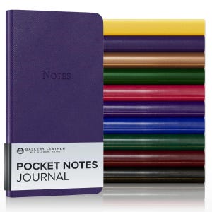 May include: A purple pocket notes journal with a textured cover and the word Notes embossed on the front. A white paper band features the text Gallery Leather Bar Harbor Maine Pocket Notes Journal. A stack of journals in various colors is visible.