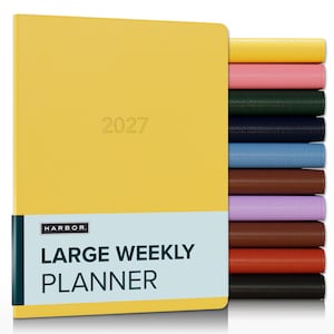 May include: A yellow 2027 large weekly planner with a light blue band featuring the text HARBOR LARGE WEEKLY PLANNER. A stack of additional planners in various solid colors including pink, green, navy, blue, brown, purple, and black is visible.