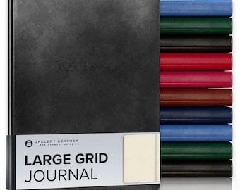 May include: A black leather-bound journal with the word JOURNAL embossed on the cover. A white paper band features the text GALLERY LEATHER BAR HARBOR, MAINE, LARGE GRID JOURNAL. A stack of journals in various colors sits to the right side.