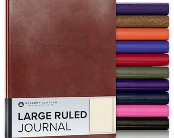 May include: A large brown leather journal with the word JOURNAL embossed on the cover. A white paper band features the text GALLERY LEATHER BAR HARBOR, MAINE LARGE RULED JOURNAL. A stack of journals in various colors is visible to the right.