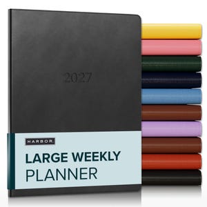 May include: A black 2027 large weekly planner with a light blue paper band featuring the text HARBOR LARGE WEEKLY PLANNER. To the right, a vertical stack of planners in various colors including yellow, pink, green, navy, blue, brown, purple, and red.
