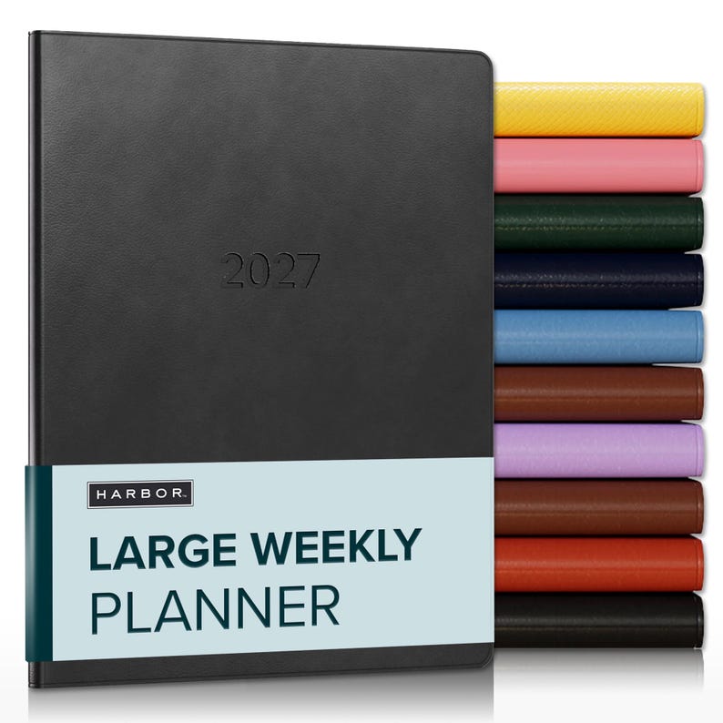 May include: A black 2027 large weekly planner with a light blue paper band featuring the text HARBOR LARGE WEEKLY PLANNER. To the right, a vertical stack of planners in various colors including yellow, pink, green, navy, blue, brown, purple, and red.