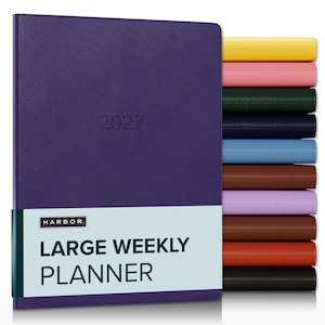 May include: A purple 2027 large weekly planner with a textured cover and a light blue paper band featuring the text HARBOR LARGE WEEKLY PLANNER. A stack of additional planners in yellow, pink, green, navy, blue, brown, lilac, tan, orange, and black.