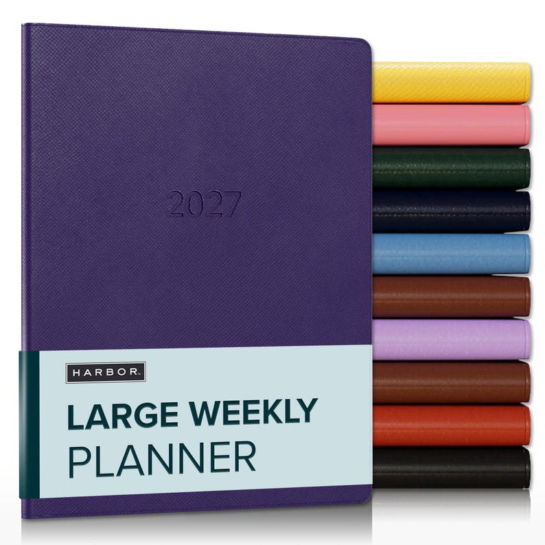 May include: A purple 2027 large weekly planner with a textured cover and a light blue paper band featuring the text HARBOR LARGE WEEKLY PLANNER. A stack of additional planners in yellow, pink, green, navy, blue, brown, lilac, tan, orange, and black.