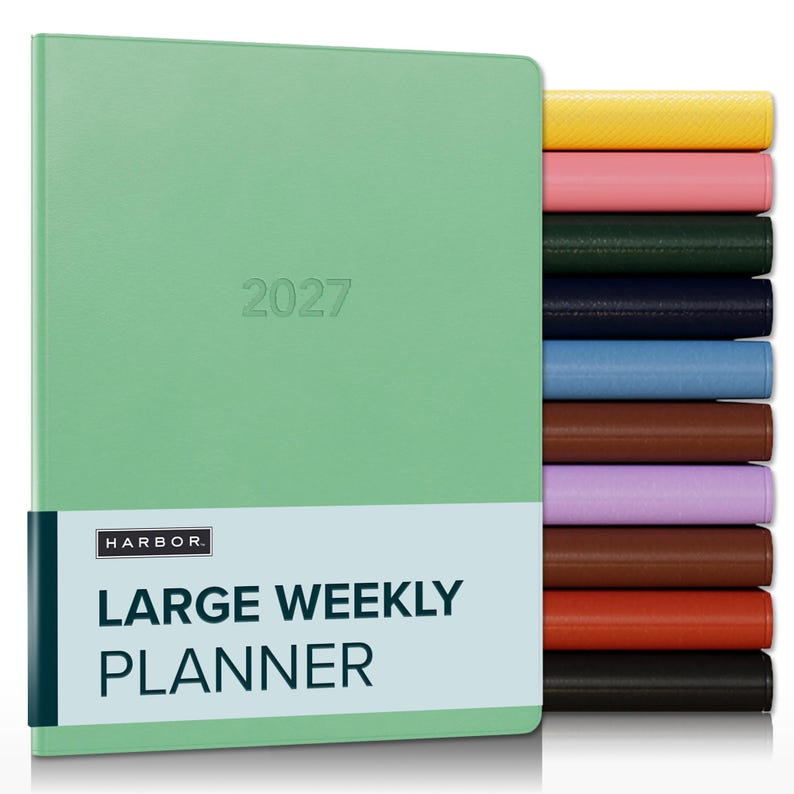 May include: A mint green 2027 large weekly planner with a paper band labeled HARBOR LARGE WEEKLY PLANNER. To the right, a vertical stack of planners in yellow, pink, dark green, navy, light blue, brown, lavender, dark brown, orange, and black.
