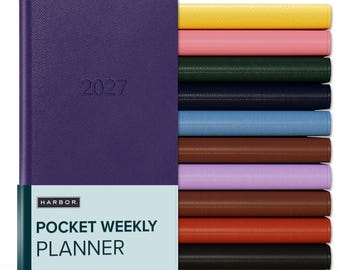 May include: A purple 2027 pocket weekly planner with a textured cover and a light blue paper band featuring the text HARBOR POCKET WEEKLY PLANNER. To the right, a vertical stack of identical planners in yellow, pink, dark green, navy, blue, brown, lilac, rust, orange, and black.