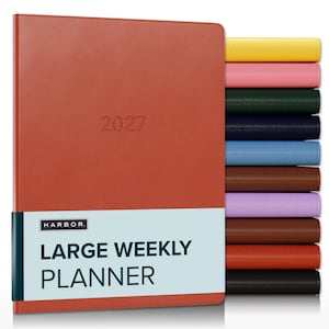 May include: A rust-colored 2027 large weekly planner with a smooth cover, featuring a light blue paper band with the text HARBOR LARGE WEEKLY PLANNER. A stack of additional planners in yellow, pink, green, navy, blue, brown, purple, and black is visible.