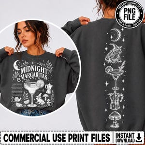 May include: A dark gray crewneck sweatshirt featuring a white graphic print. The front displays the text "MIDNIGHT MARGARITAS" with illustrations of a margarita glass, a frog wearing a witch hat, a coffee maker, a snail, and mushrooms.