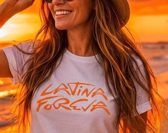 May include: A white short-sleeved t-shirt with the orange text "LATINA FOREVA" printed on the front. The shirt is paired with blue denim shorts featuring distressed details and frayed hems. The garment is worn with a straw hat and sunglasses.