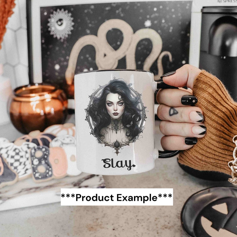 May include: White ceramic mug with a black rim and handle. The mug features a black and white illustration of a woman with long dark hair and a black and white ornate design around her. The text "Slay" is printed in black below the illustration.