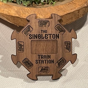 May include: A wooden train station sign with the text "The Singleton Train Station" and a cutout in the shape of a train engine.