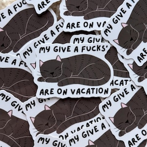 May include: A collection of white stickers featuring a sleeping black cat illustration. The stickers have the text "MY GIVE A FUCKS ARE ON VACATION" in a playful font. The cat has pink ears and a relaxed expression.