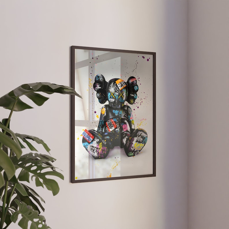 May include: A framed print of a black and white graffiti-style illustration of a cartoon character with a black background and colourful accents.
