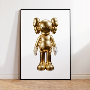 May include: A gold-coloured figurine of a cartoon character with white hands and a black X for eyes. The figurine is standing on a white background.