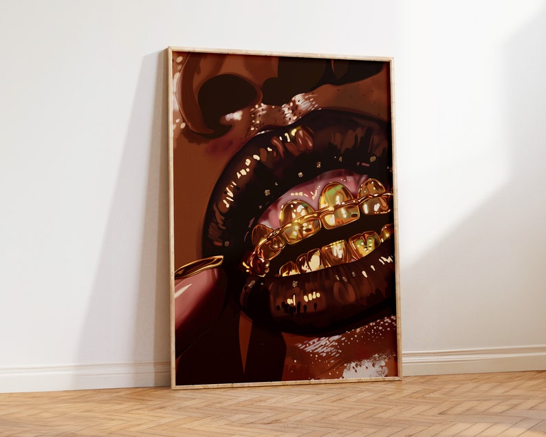 Pode incluir: Uma impress&atilde;o de arte emoldurada com um close-up de uma boca com l&aacute;bios castanhos escuros e brilhantes e grelhas de dentes douradas. A obra de arte tem uma paleta de cores quentes com tons de castanho e dourado.