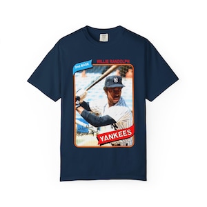 Puede incluir: Camiseta azul marino con un diseño de tarjeta de béisbol vintage. La tarjeta muestra a Willie Randolph de los Yankees, con el logotipo y el nombre del equipo. La camiseta tiene cuello redondo y mangas cortas.