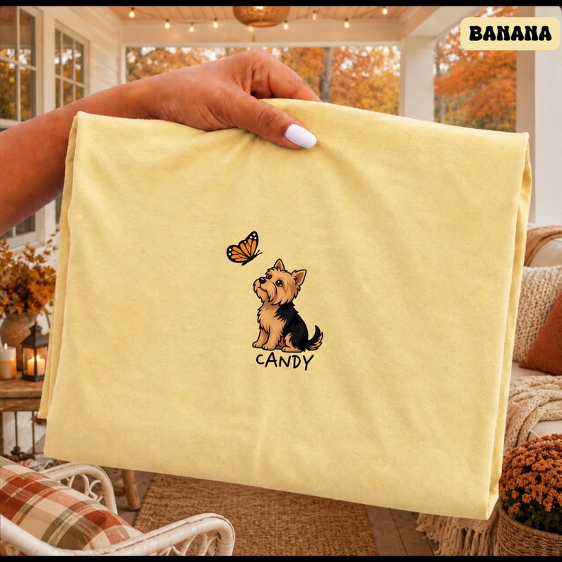 Folded BANANA Comfort Colors shirt with cute Yorkshire Terrier puppy and butterfly graphic, personalized dog lover tee with custom pet name, minimalist pet shirt flat lay aesthetic gift idea.