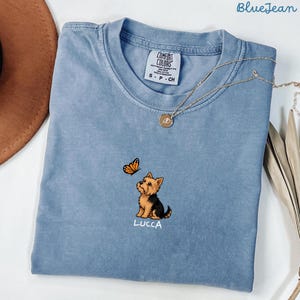 Folded BLUE JEAN Comfort Colors shirt with cute Yorkshire Terrier puppy and butterfly graphic, personalized dog lover tee with custom pet name, minimalist pet shirt flat lay aesthetic gift idea.