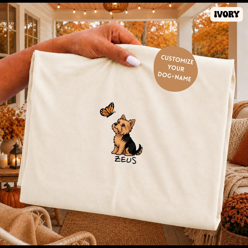 Folded IVORY Comfort Colors shirt with cute Yorkshire Terrier puppy and butterfly graphic, personalized dog lover tee with custom pet name, minimalist pet shirt flat lay aesthetic gift idea.