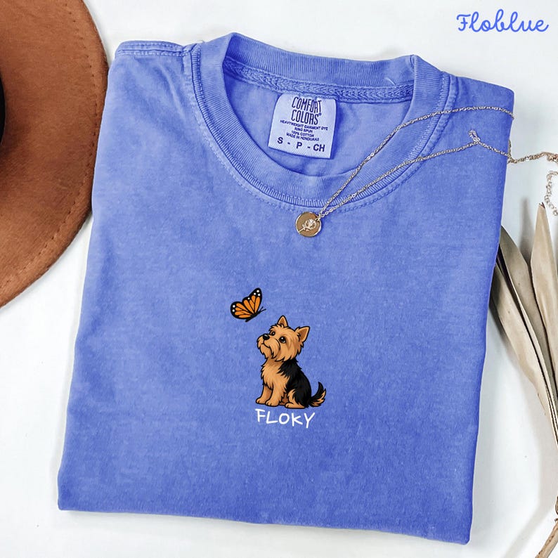 Folded FLO BLUE   Comfort Colors shirt with cute Yorkshire Terrier puppy and butterfly graphic, personalized dog lover tee with custom pet name, minimalist pet shirt flat lay aesthetic gift idea.