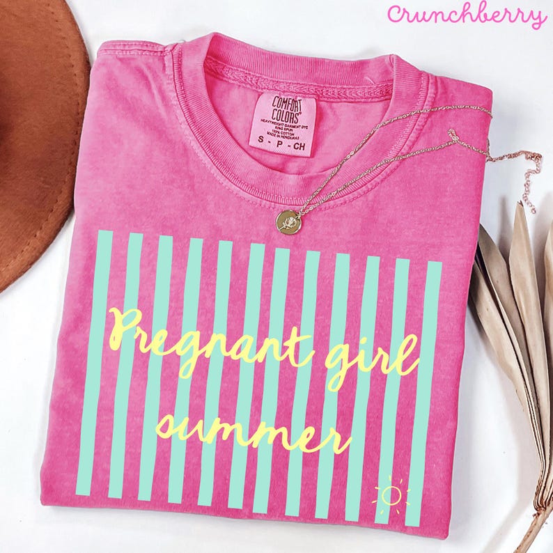 Crunchberry pink Comfort Colors shirt with vertical mint green stripes and yellow script text reading “Pregnant girl summer” centered across the front, with a small yellow sun icon detail at the bottom corner.